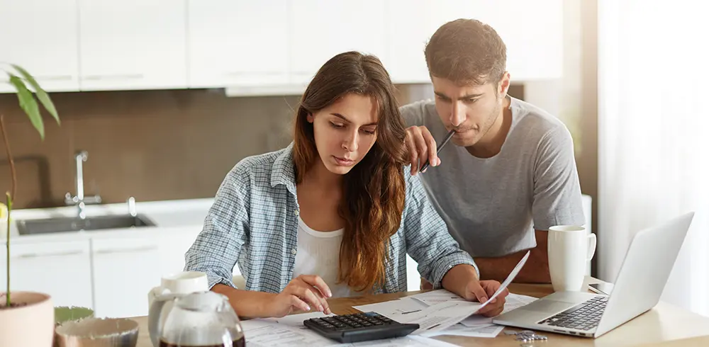 A couple sitting together at a table, happily planning their finances