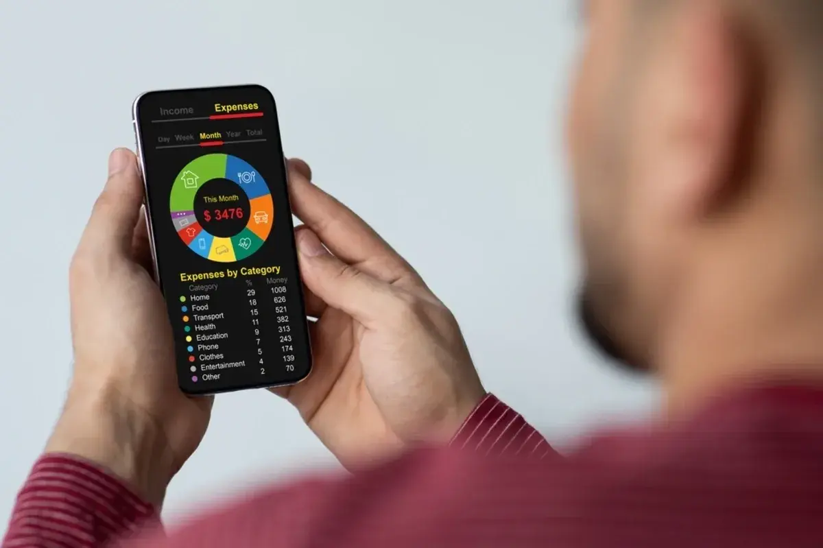 A person using a budgeting app on their smartphone to track expenses